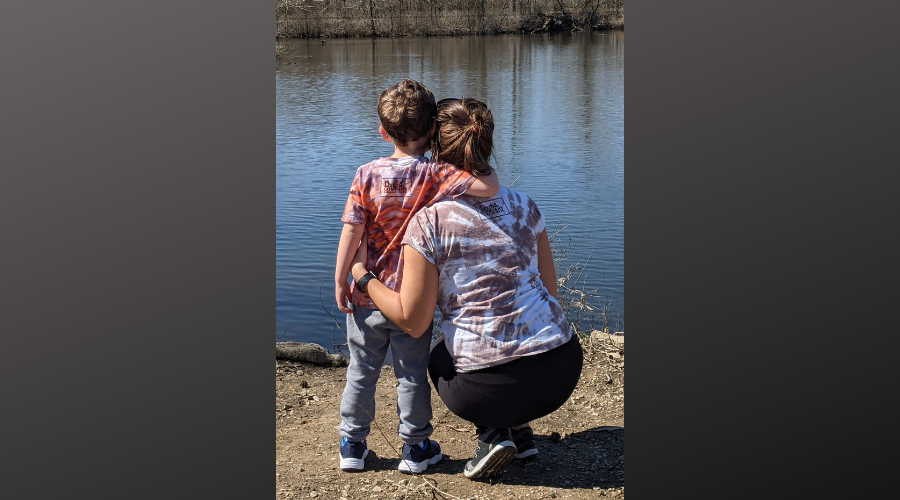 Photo of woman and young boy from behind looking out over water wearing tie dye