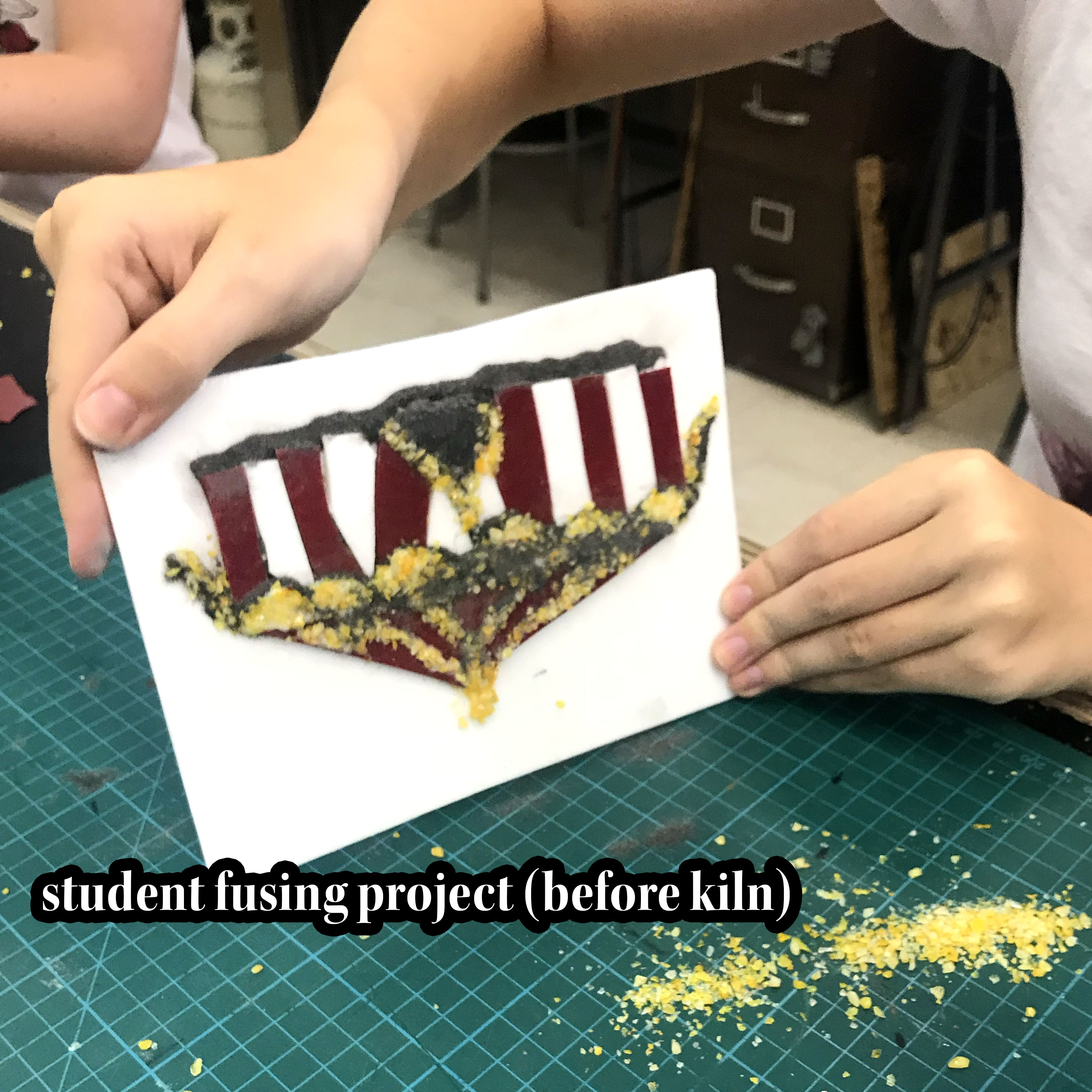 student tapping off excess glass from their fusing project. image is of a circus tent