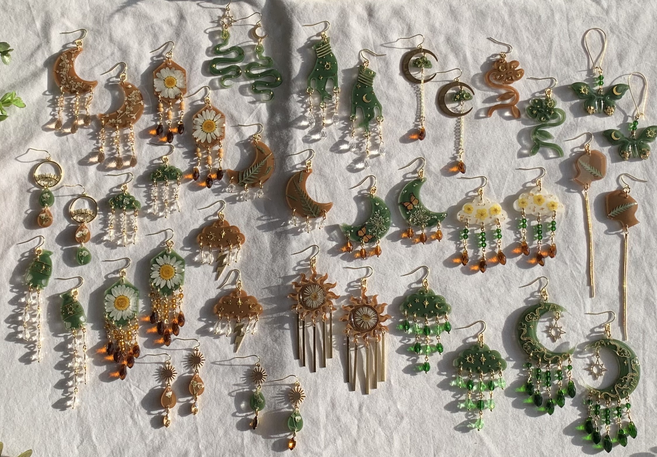 the entire earth collection of earrings laid out next to each other, there is browns, greens, and lots of dangles