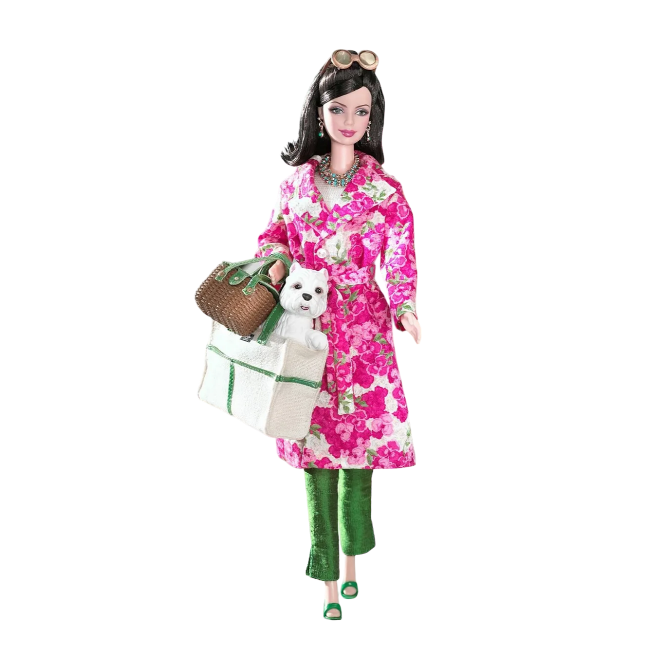 Kate Spade Barbie doll wearing green trousers and a floral trench coat, carrying a picnic basket and tote bag with a white westie dog in it.