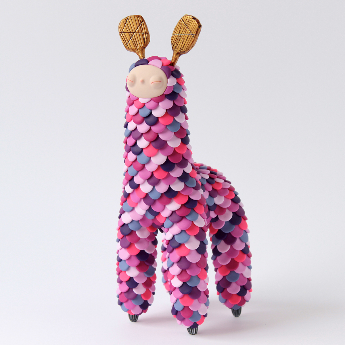 Polymer clay sculpture of an imaginary lama with colorful scales and antlers