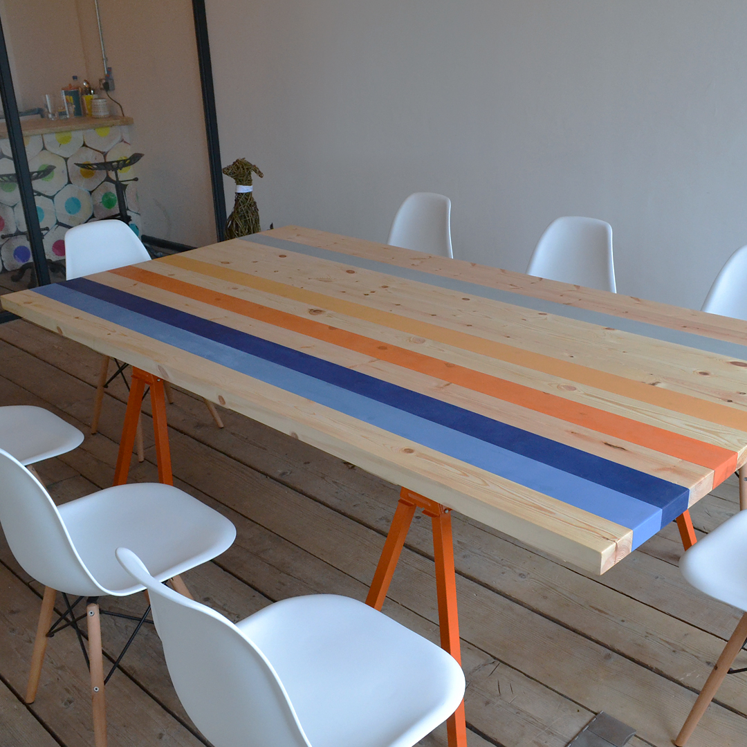 Striped table with bright orange legs and white plastic chairs