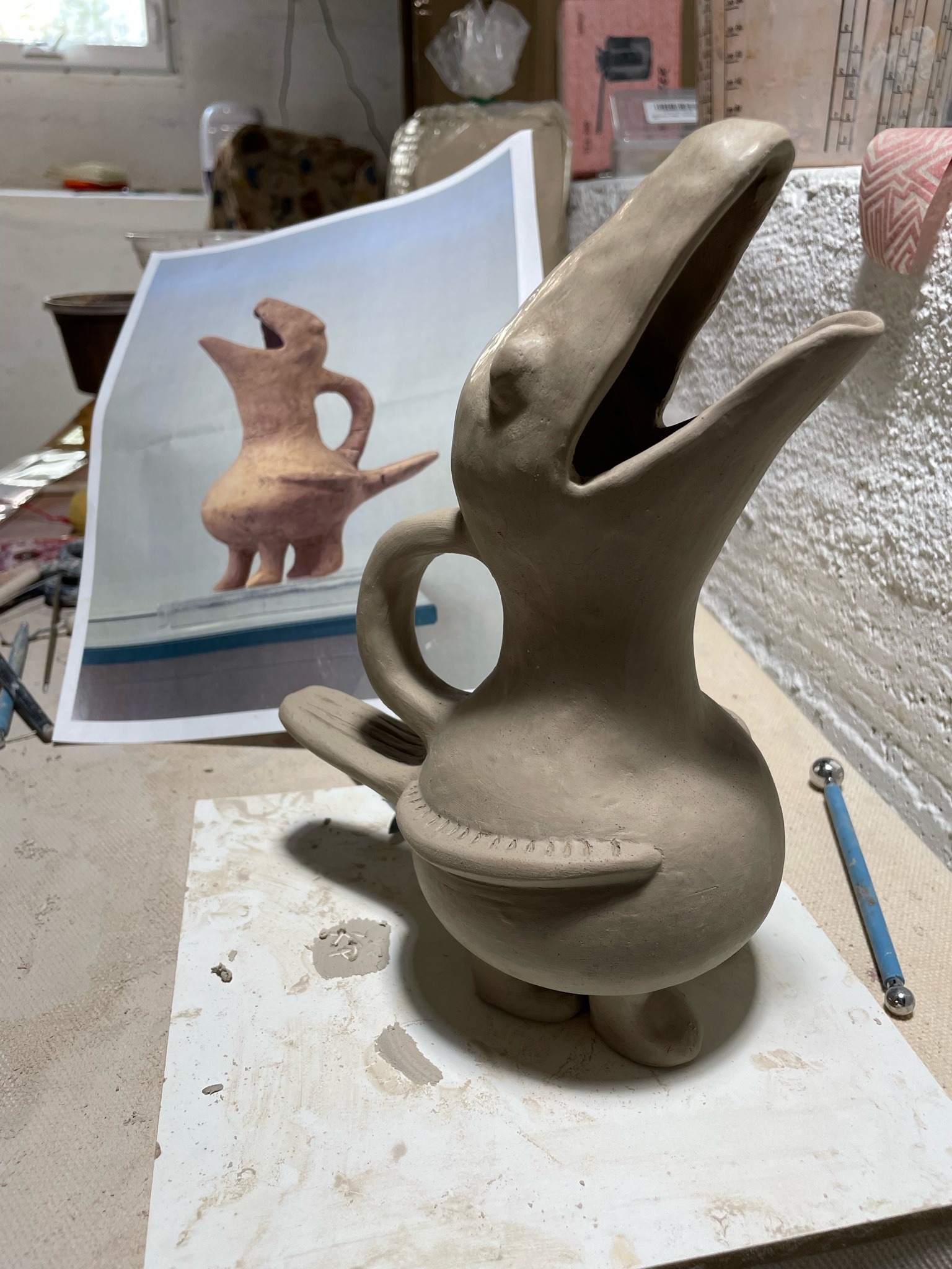 Jug shaped like a bird with a museum reference photo in the background