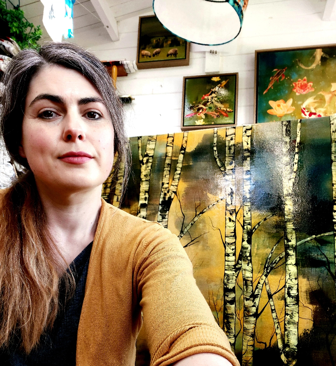 Lily Greenwood in her studio, with a golden hued silver birch canvas behind