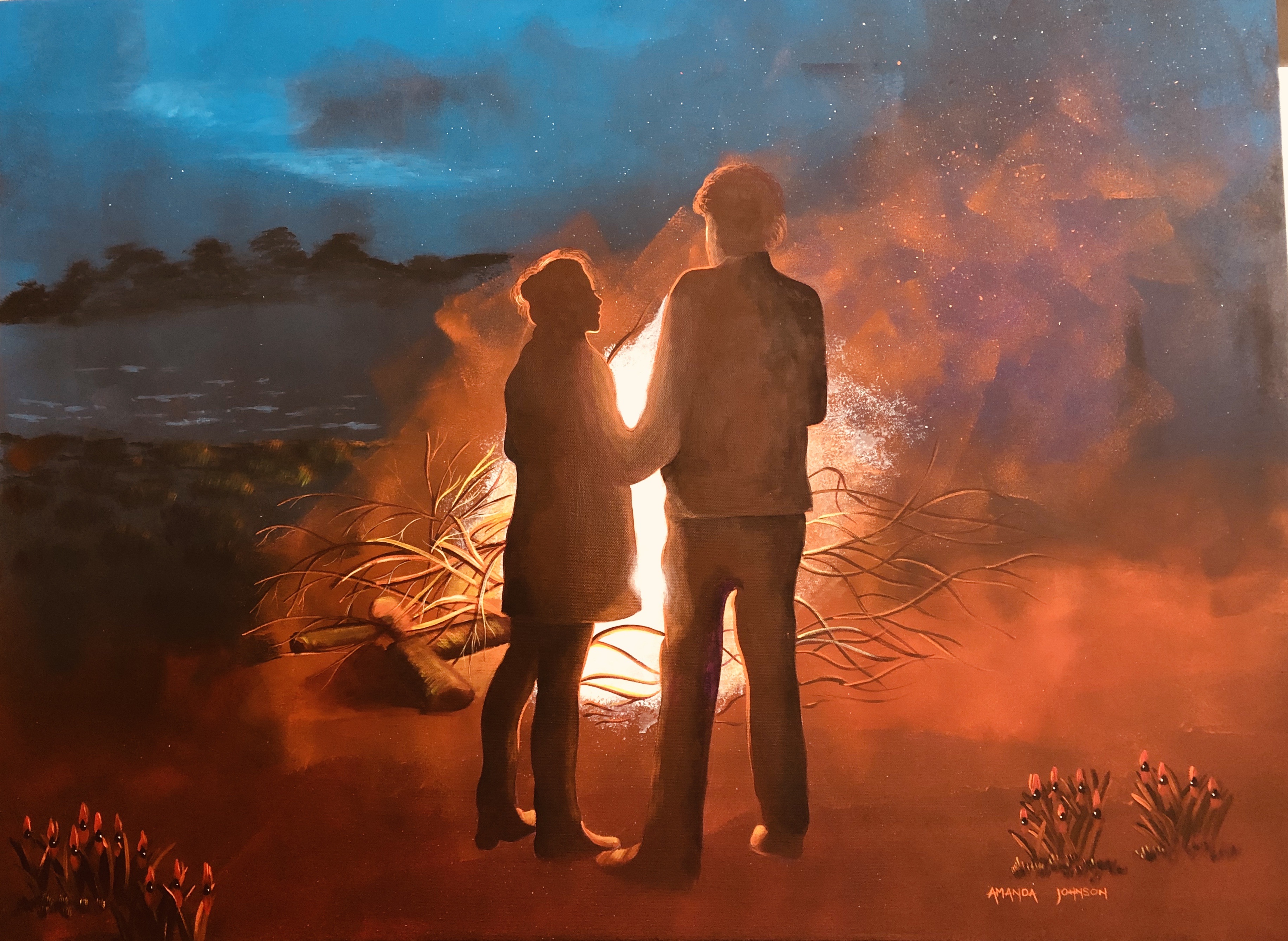 A woman and a man are shadows in front of a large campfire and a glorious starry night