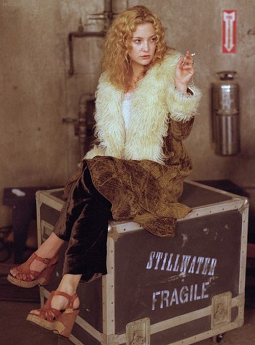 Kate Hudson as Penny Lane in Almost famous sat on a black box wearing a brown shearling coat