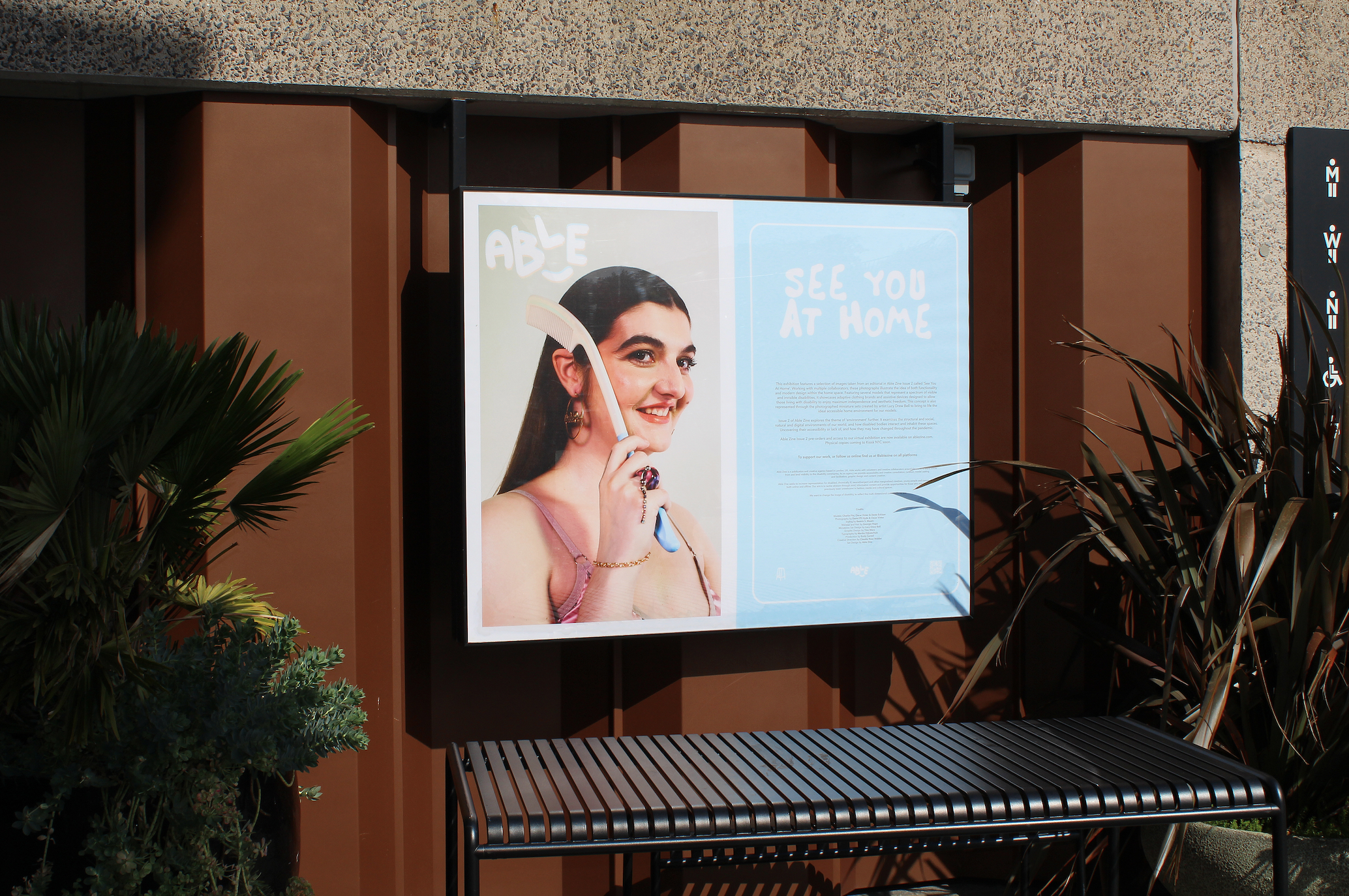 An image of the first lightbox at the outdoor exhibition. It shows a title and text describing the exhibition on one side, and on the other, a portrait photograph of model Charlie using an adaptive haircomb and looking directly into the camera
