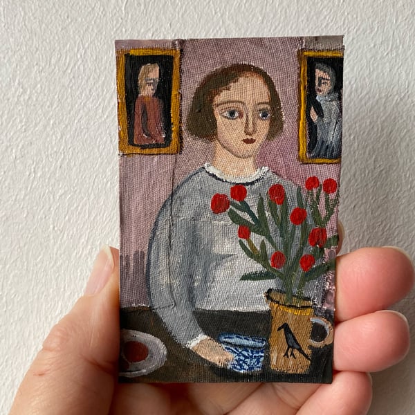 Image of Woman at a table with bird jug and red flowers - tiny painting 