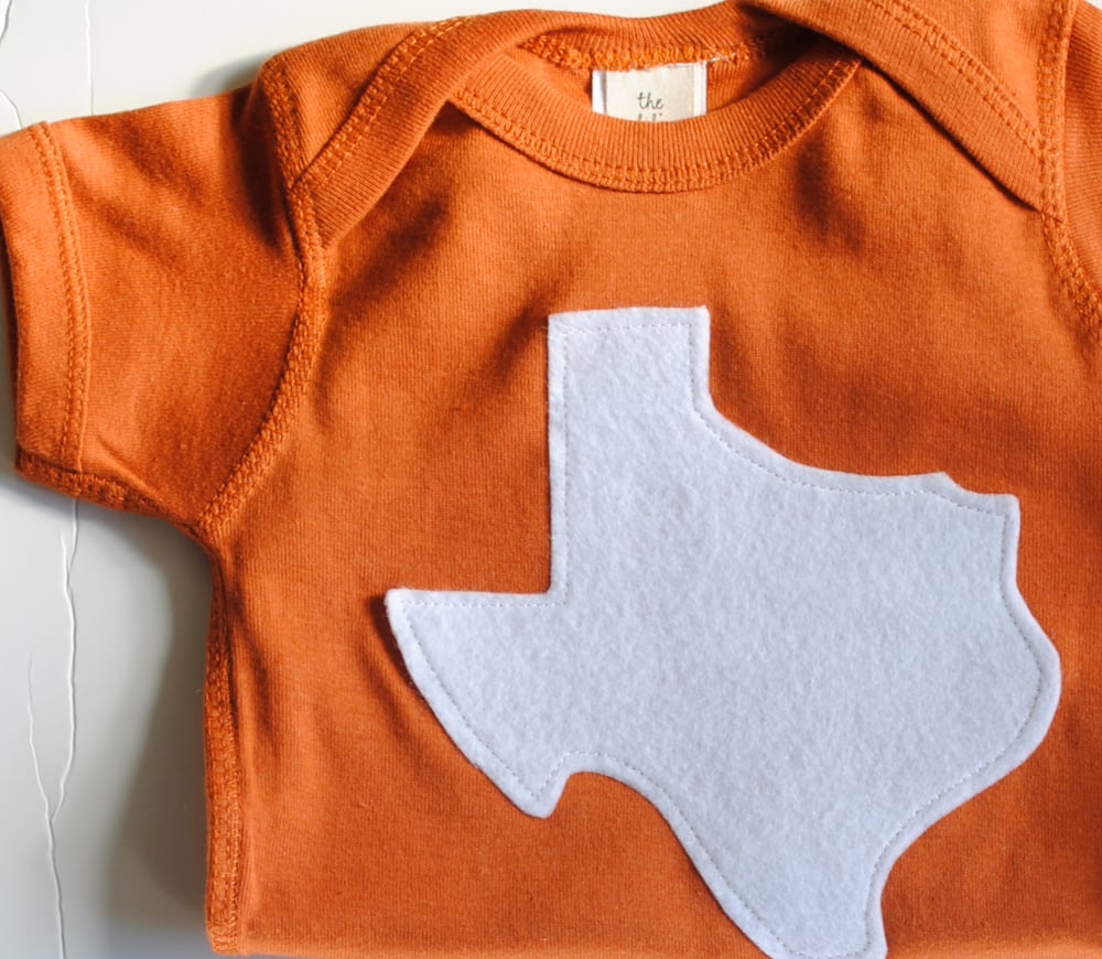 Image of burnt orange and white Texas onesie
