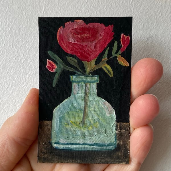 Image of crimson roses in an old ink bottle