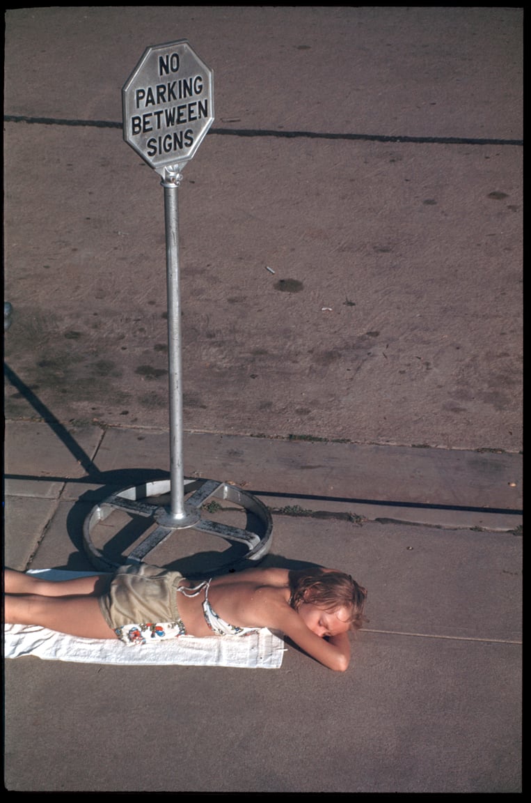 Image of A Young Girl Sunbathes On The Sidewalk: 1960's