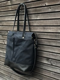 Image 1 of Black waxed canvas tote bag with leather bottom handles and cross body strap
