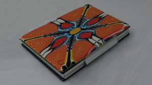 Image of Orange and yellow spiral polymer on leather and aluminum case (Rhyl Collection)