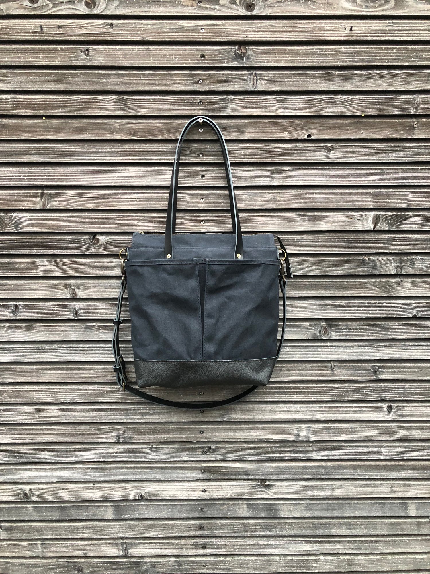 Image of Black waxed canvas tote bag with leather bottom handles and cross body strap