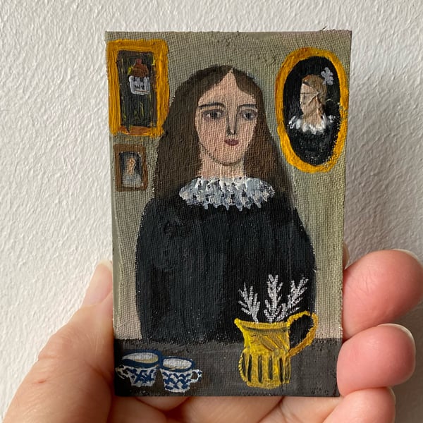 Image of Woman in black at a table with jug of feathers - tiny portrait 