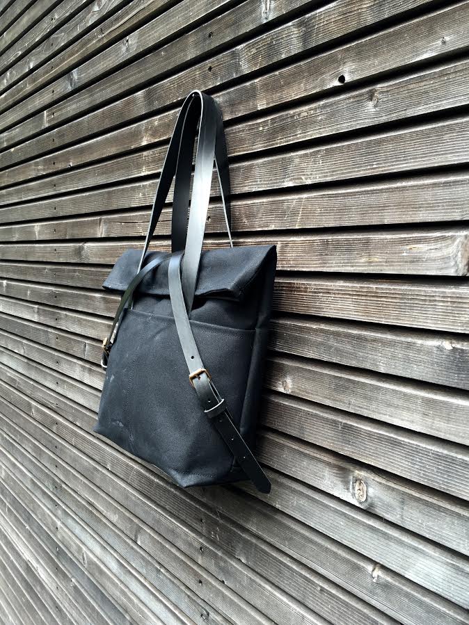 Black waxed canvas tote bag with leather bottom handles and cross body strap