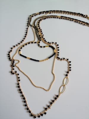 Image of Vita. Collar largo de tres vueltas en dorado y negro.