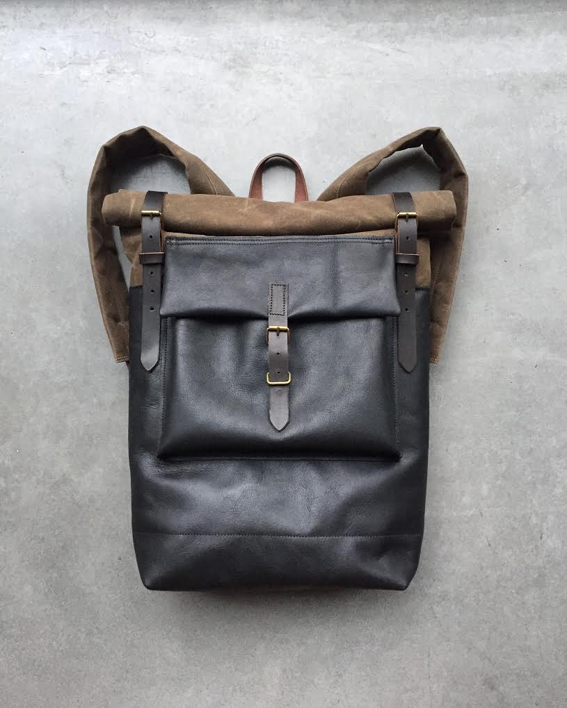 Image of Black leather backpack with waxed canvas roll to close top and leather front pocket