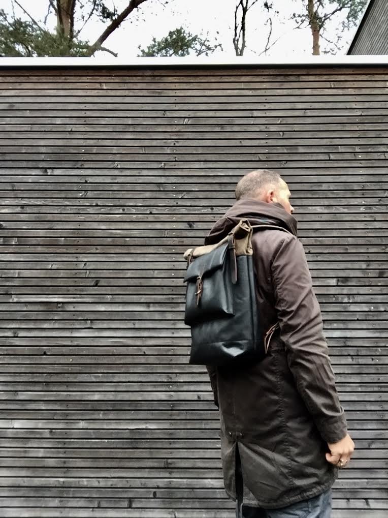 Image of Black leather backpack with waxed canvas roll to close top and leather front pocket
