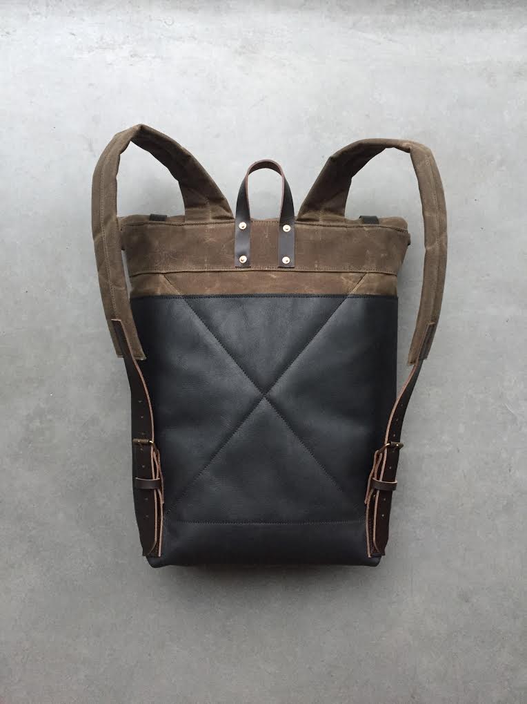 Image of Black leather backpack with waxed canvas roll to close top and leather front pocket