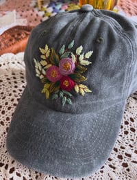 Image 1 of Purple hand embroidered flowers on an adjustable dark green fabric hat
