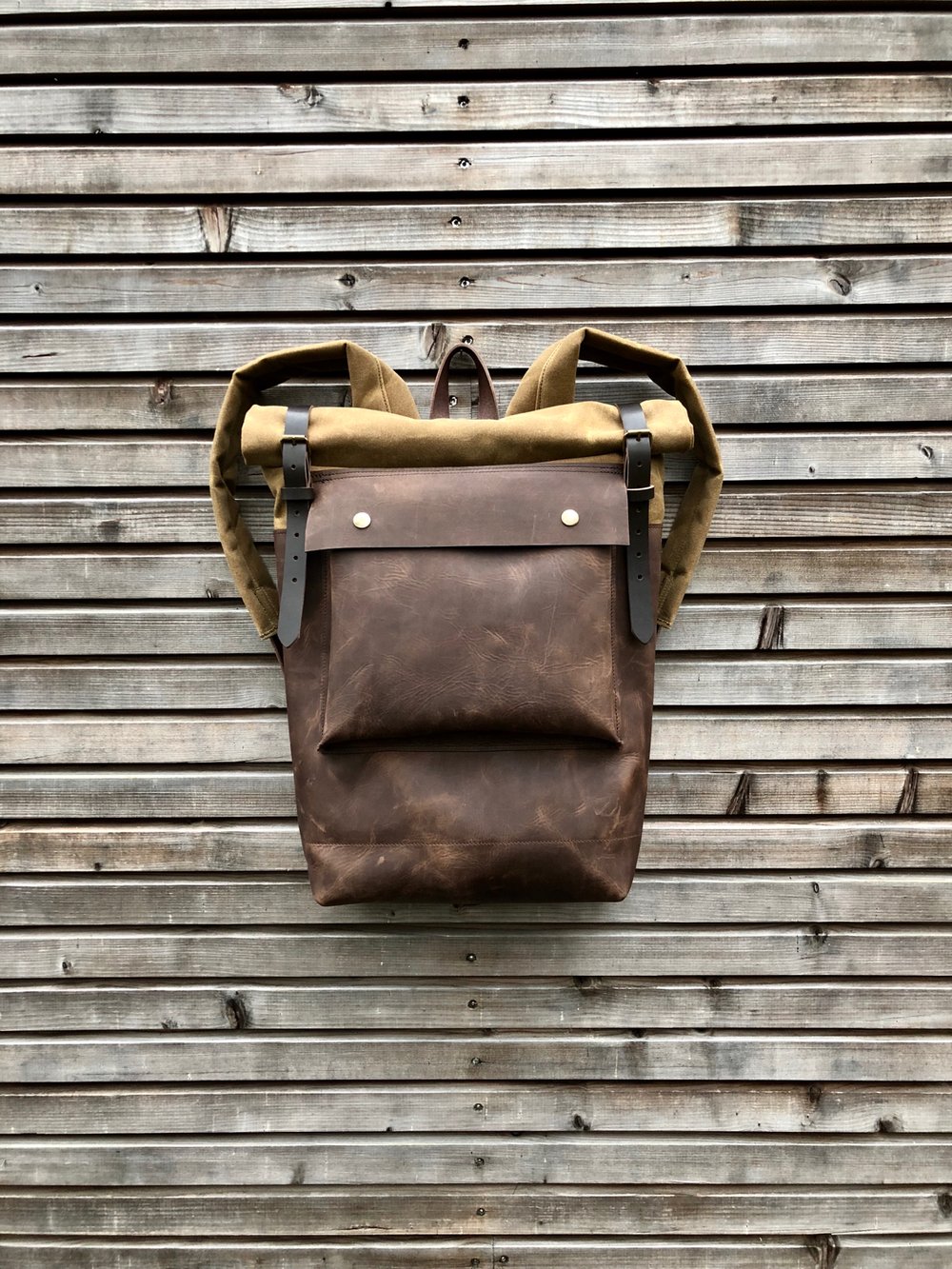 Image of Leather backpack with waxed canvas roll to close top and leather front pocket