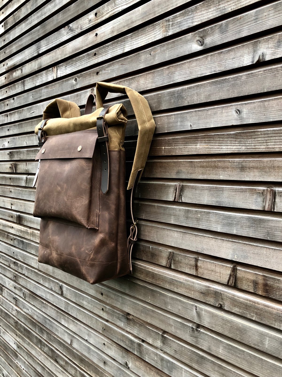 Image of Leather backpack with waxed canvas roll to close top and leather front pocket