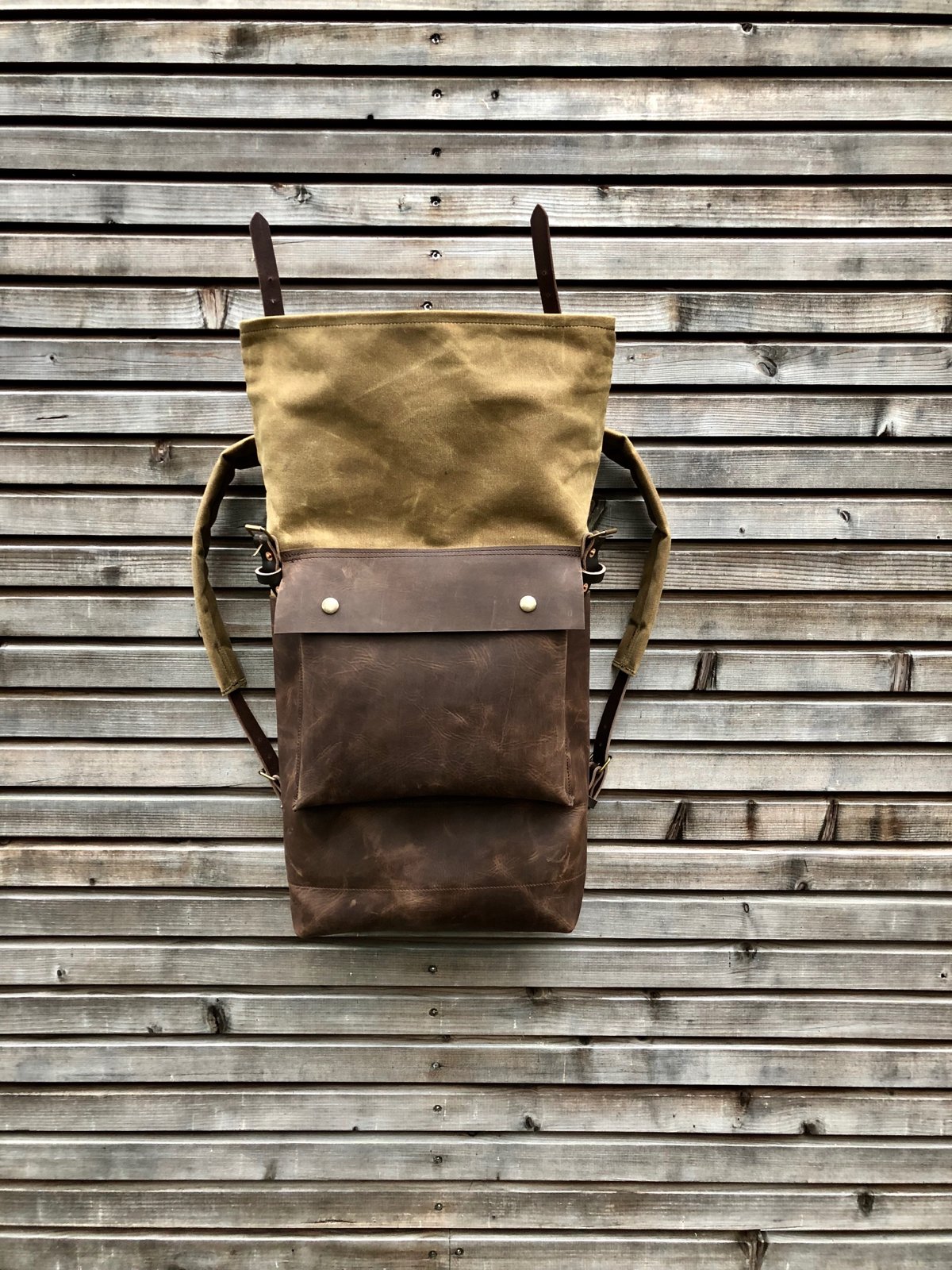 Image of Leather backpack with waxed canvas roll to close top and leather front pocket