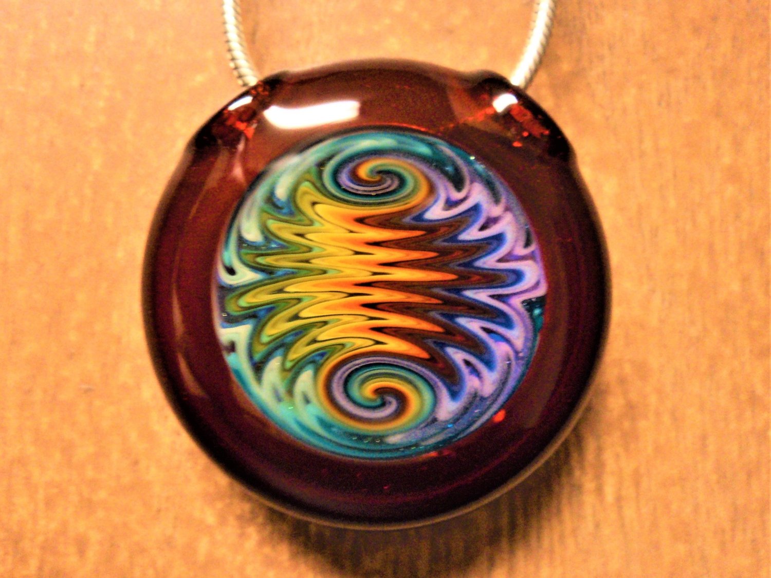 Image of GUS GLASS RED ELVIS HOLLOW DISC PENDANT WITH 31 - LINE RAINBOW WIG WAG