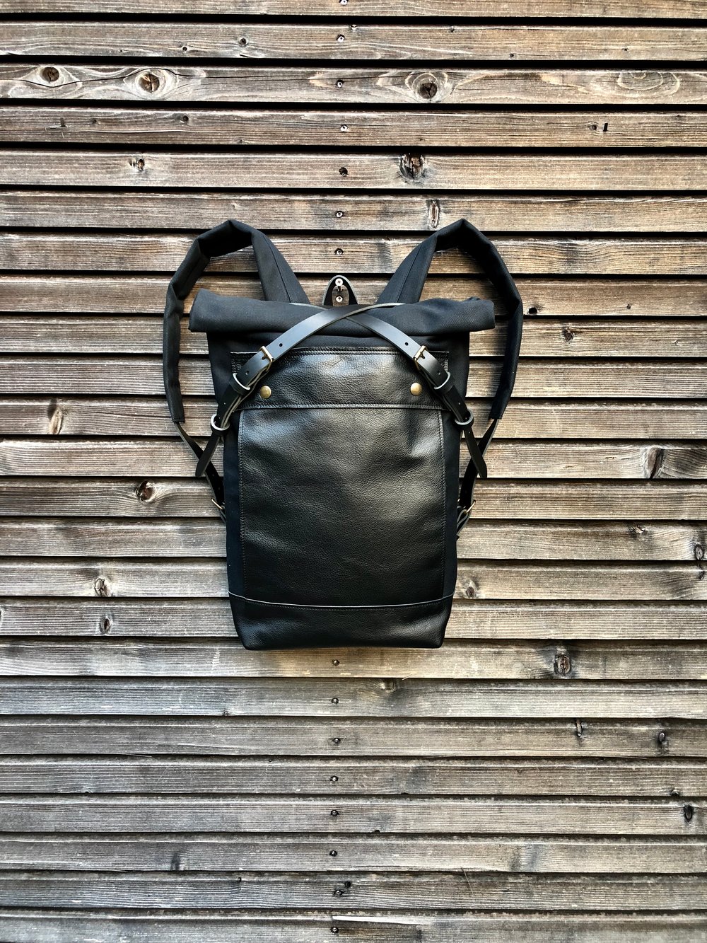 Black leather backpack with waxed canvas roll to close top and leather  front pocket