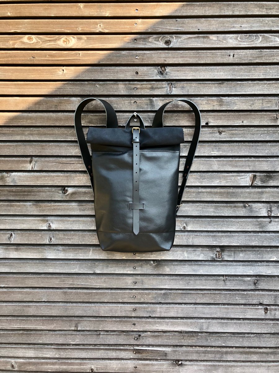 Image of Black leather backpack with waxed canvas roll to close top