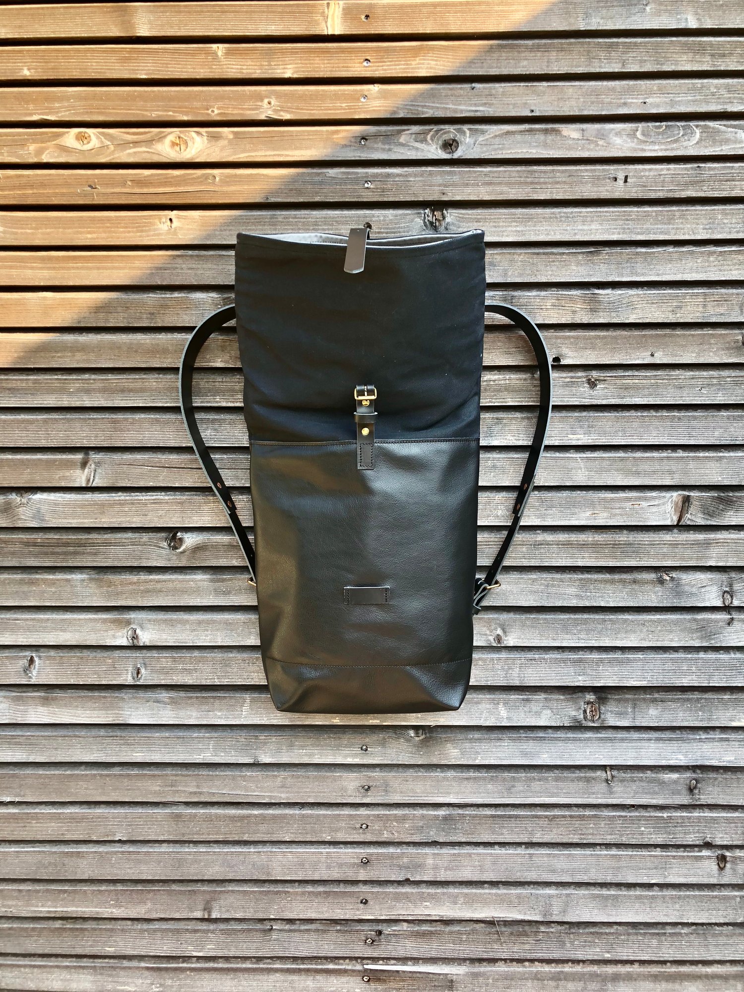 Image of Black leather backpack with waxed canvas roll to close top
