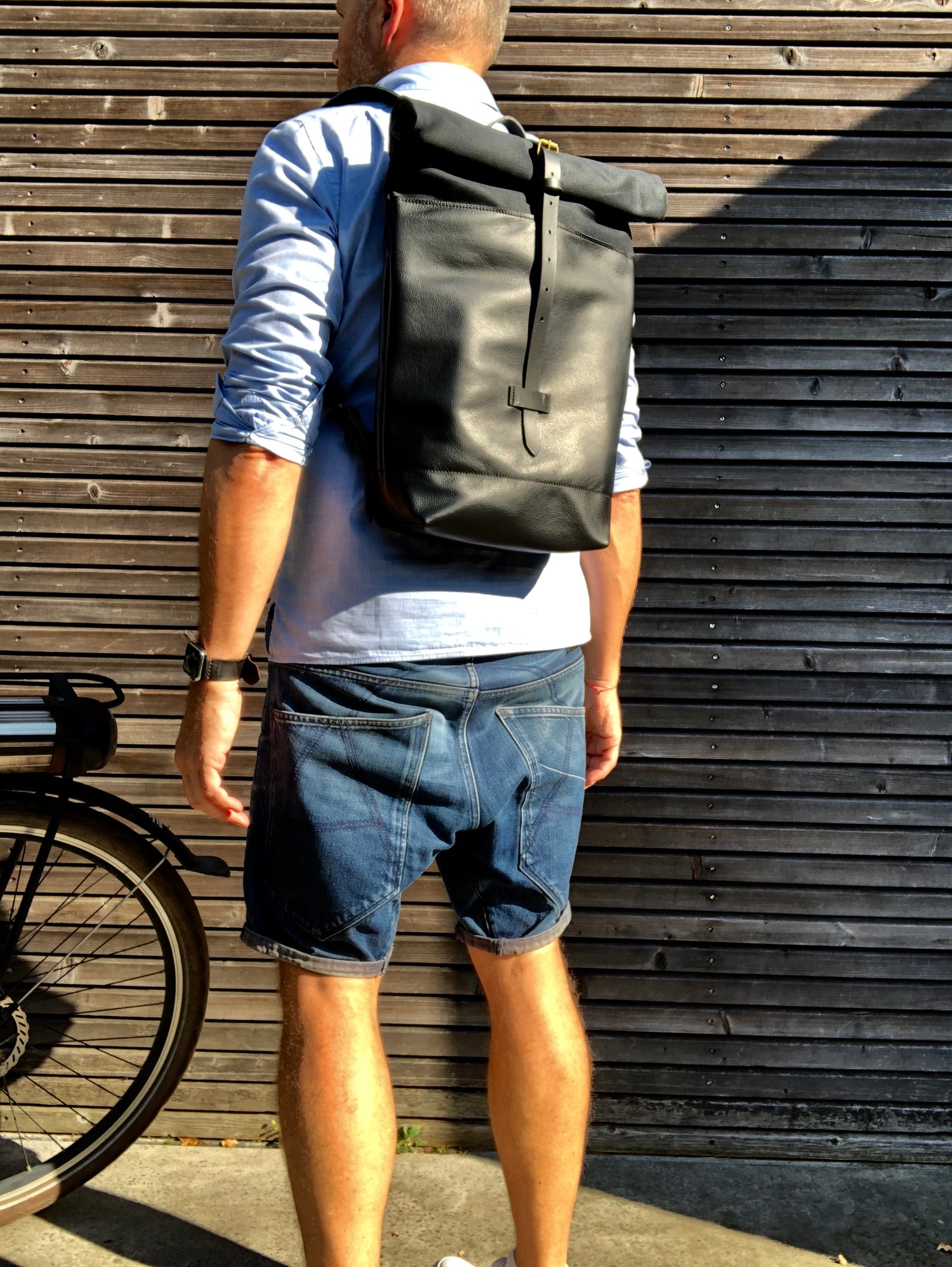 Image of Black leather backpack with waxed canvas roll to close top
