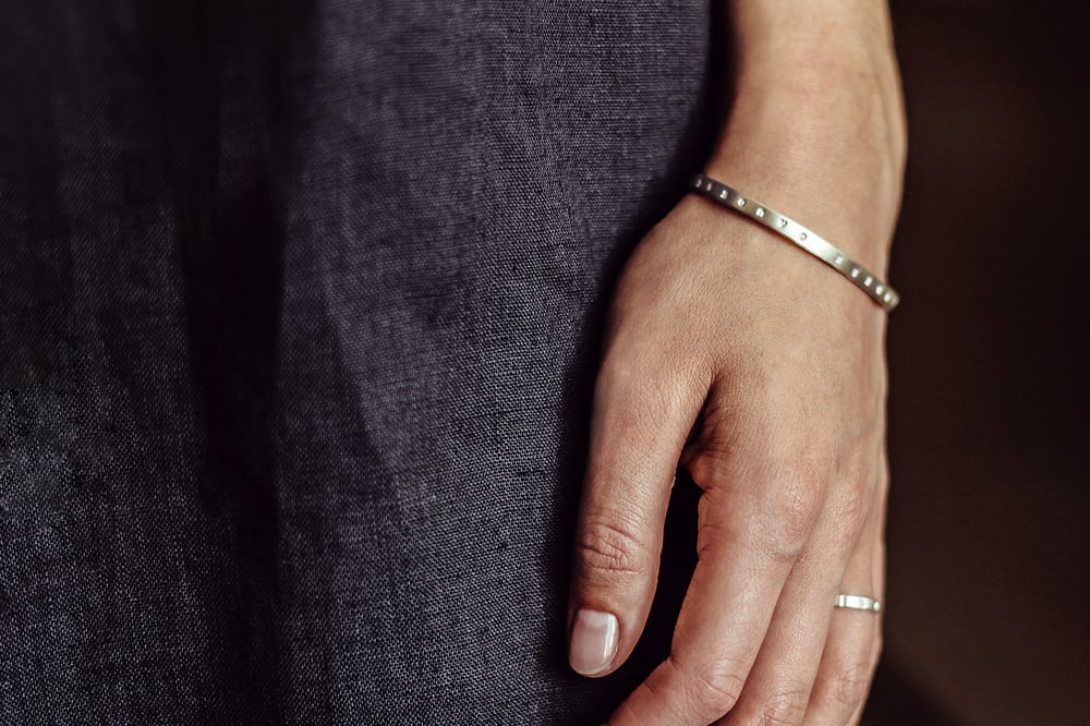 Image of thin silver bracelet with inscription in Latin
