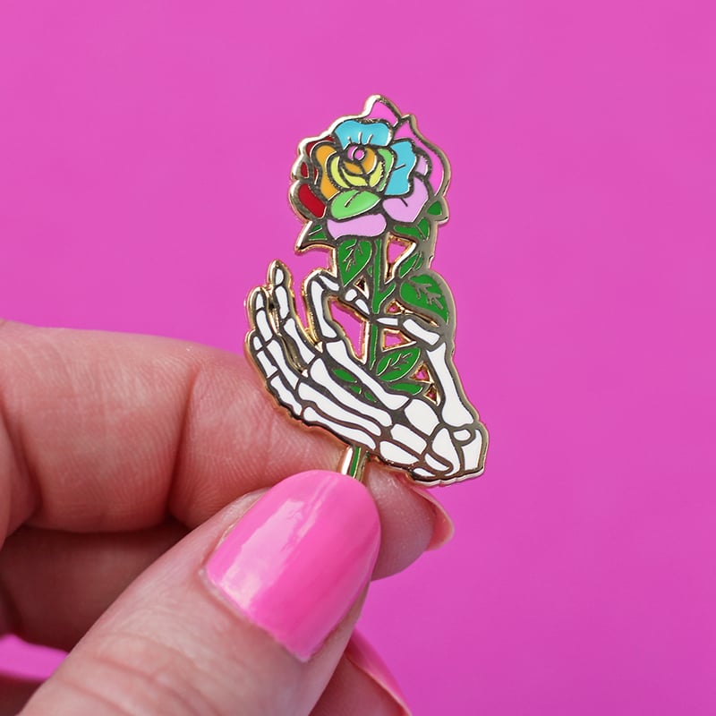 Image of Skeleton hand holding a rainbow rose, enamel pin - bones - skeleton pin - anatomy - lapel pin badge