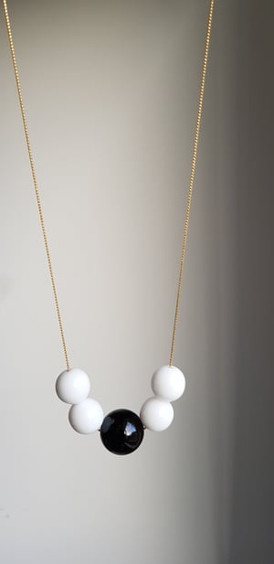 Image of Dominó. Collar largo con encantos en blanco y negro.