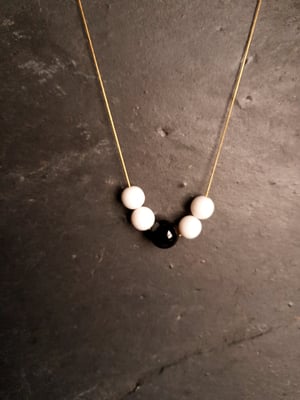 Image of Dominó. Collar largo con encantos en blanco y negro.