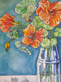 Image 1 of Orange Nastursiums in a blue glass vase