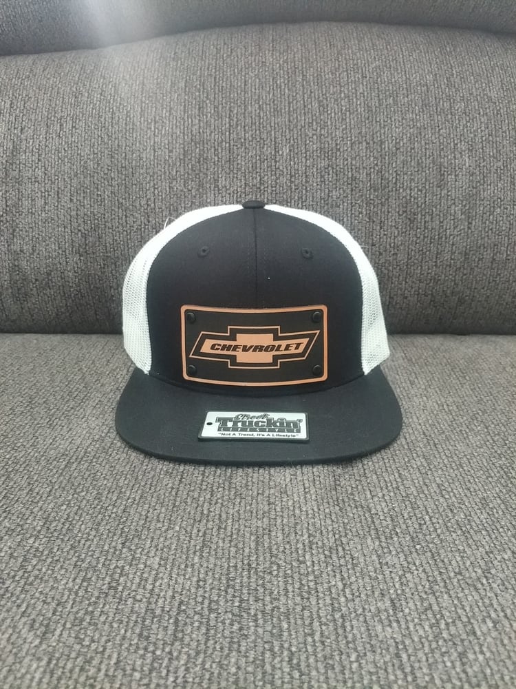 Image of Chevrolet black trucker hat with white mesh. Snapback cap. Badge is 100% leather