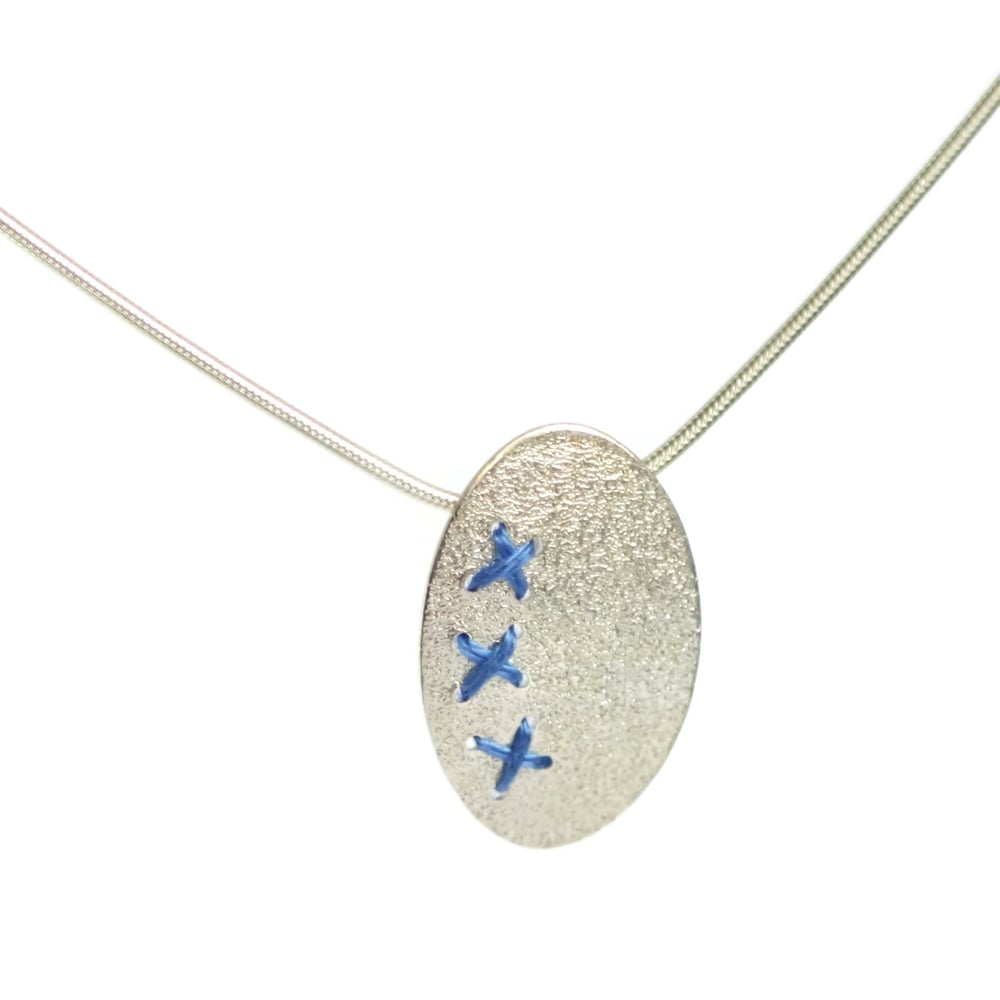 Image of Sewn Up oval pendant with 3 kisses