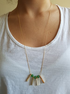 Image of Valentina (mediano). Collar largo con detalle de piedra semipreciosa y charms en dorado.