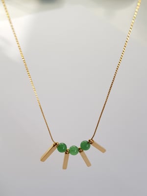 Image of Valentina (mediano). Collar largo con detalle de piedra semipreciosa y charms en dorado.