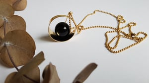 Image of Galatea. Collar largo con cadena de bolas, detalle de anillo dorado y cuenta semipreciosa de ónix