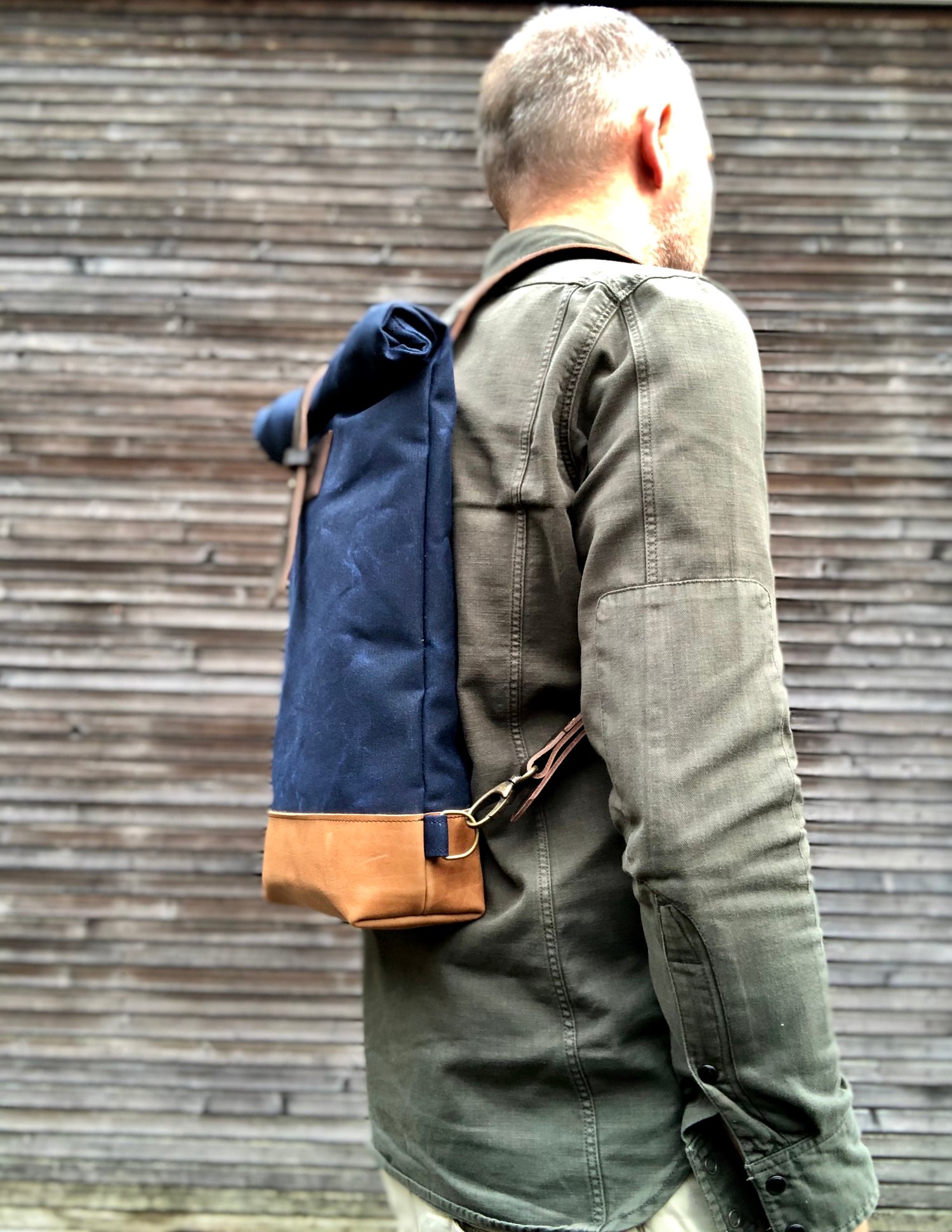 Image of Small waxed canvas backpack in navy blue with rolled top and leather shoulder straps