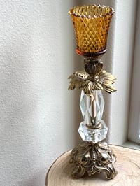Image 1 of Vintage candlestand made of brass and lucite with a diamond cut amber votive. 