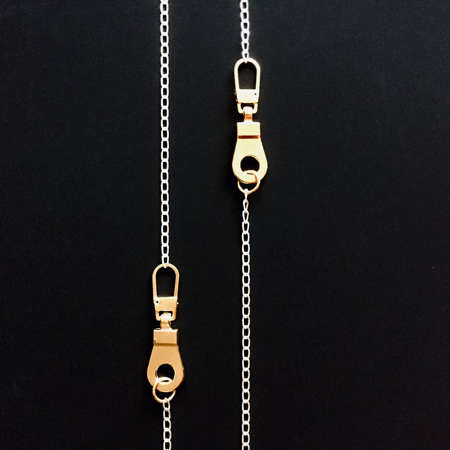 LONG AND LEAN WITH GOLDEN ZIP CHARMS THAT GROOVES THE RHYTHM 

Open structure sterling silver chain with two goldplated hardware zips.
The chain consist a total length of 90cm / 35,45" 
Wondrous in sentiment, calm and elegant in proportions.
