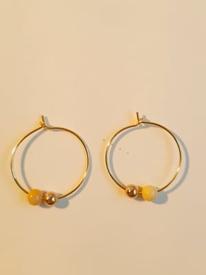 Image of Micaela. Pendietes de aro. Criollas doradas con dos encantos en forma de bola.