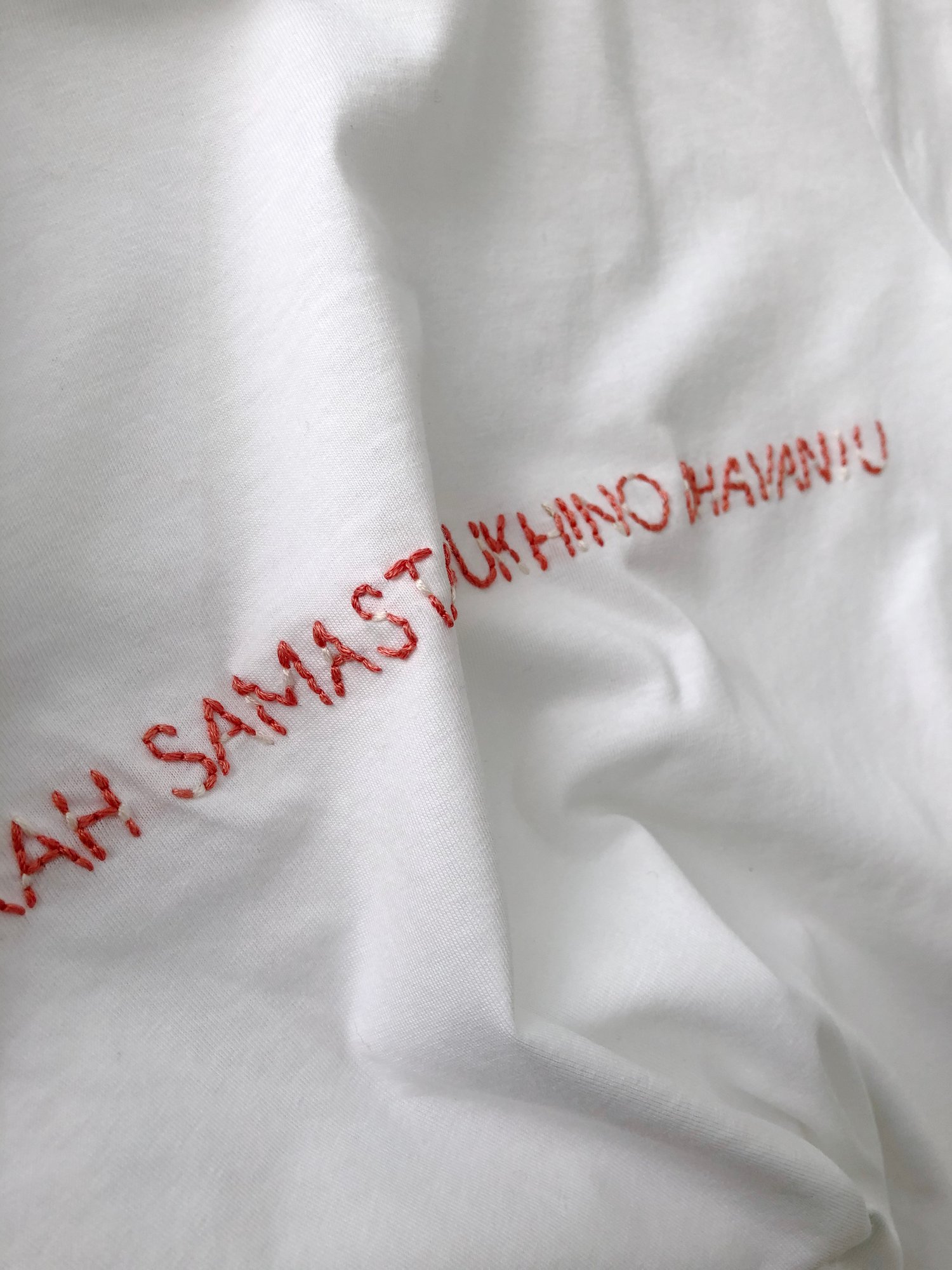 Image of LOKAH SAMASTAH SUKHINO BHAVANTU – red/beige – white t-shirt w/ rolled-up sleeves – 