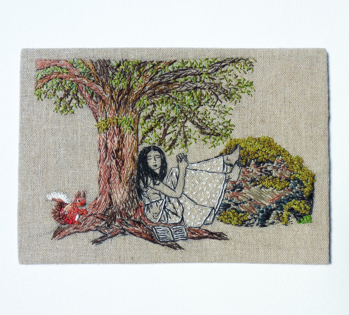 Image of young woman sitting under a tree - embroidery artwork