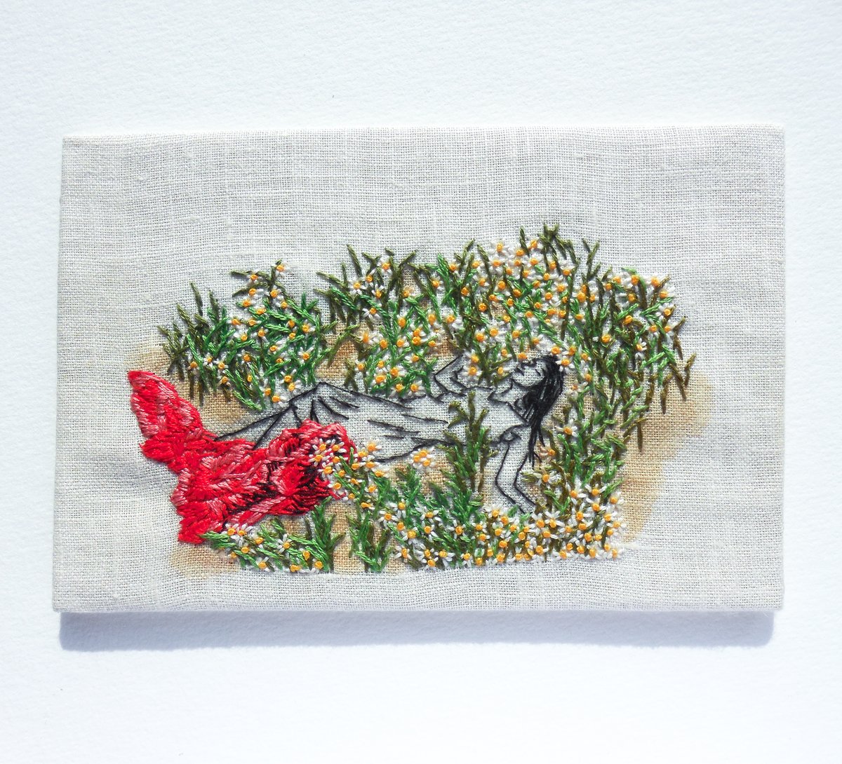 Image of woman laying in a field of wildflowers - embroidery artwork